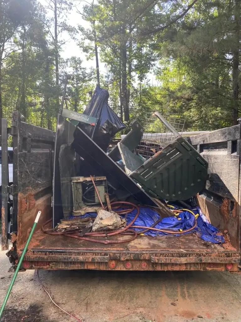 Toss It dump trailer loaded with tires, household debris, and yard items during a rental property cleanout in Auburn, Alabama